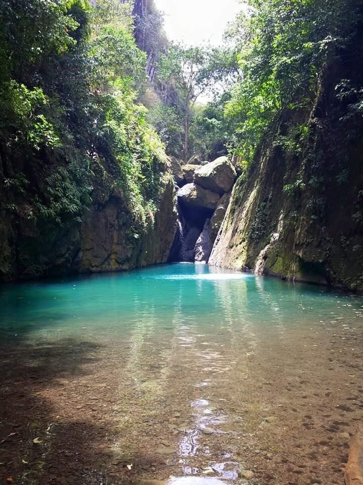 A turquoise canyon pool beneath towering rock walls